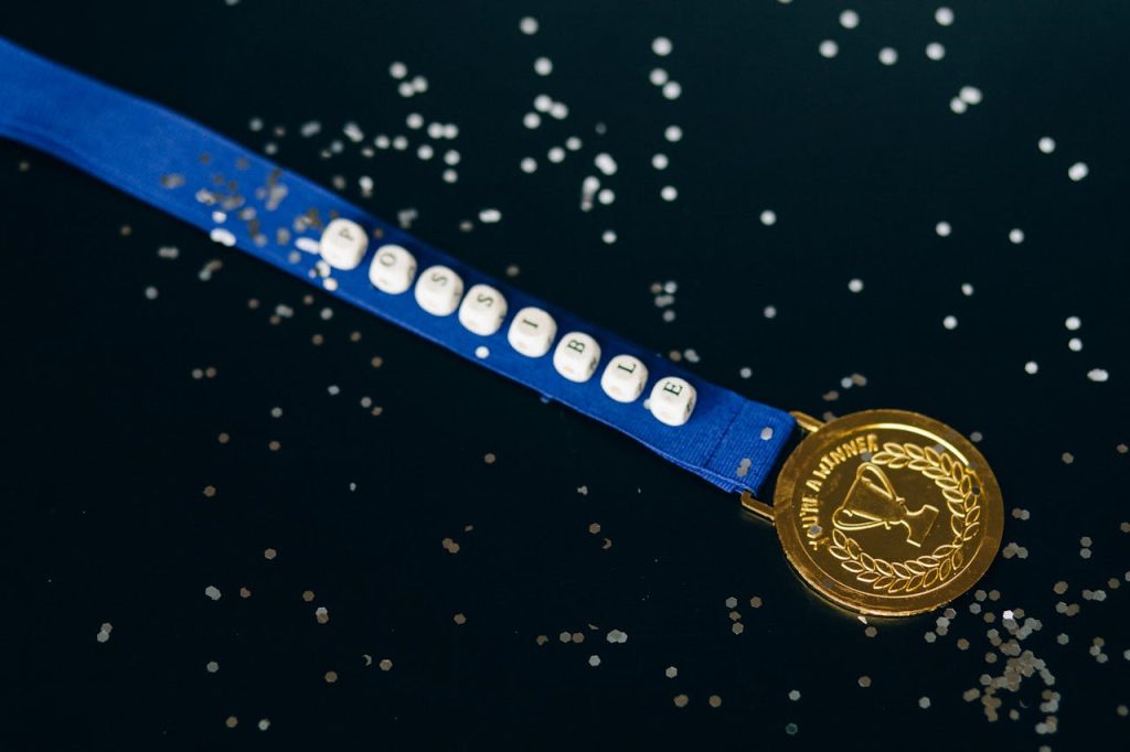 Close-up of a gold medal on a blue ribbon with possible beading, symbolizing achievement.